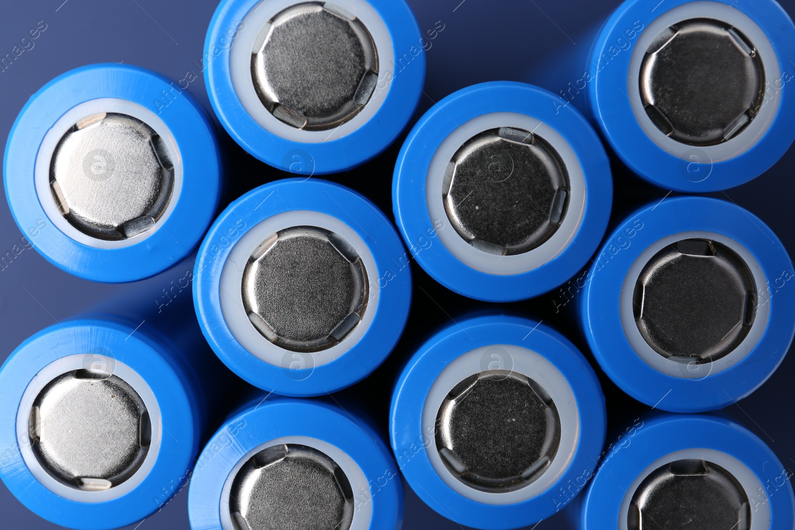 Photo of Many AA cell batteries on blue background, top view