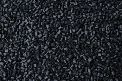 Photo of Pile of black plastic granules as background, top view