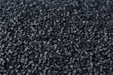 Photo of Pile of black plastic granules as background, closeup