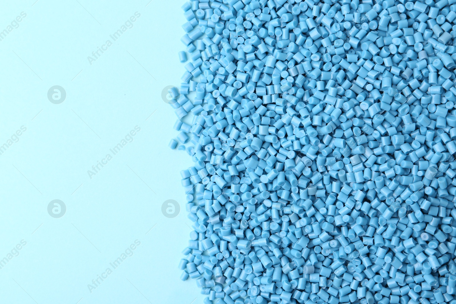 Photo of Pile of plastic granules on light blue background, top view. Space for text