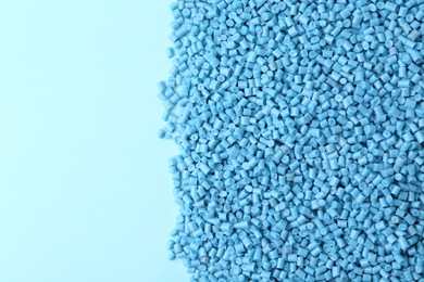 Photo of Pile of plastic granules on light blue background, top view. Space for text