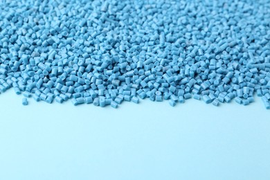 Photo of Pile of plastic granules on light blue background, closeup. Space for text