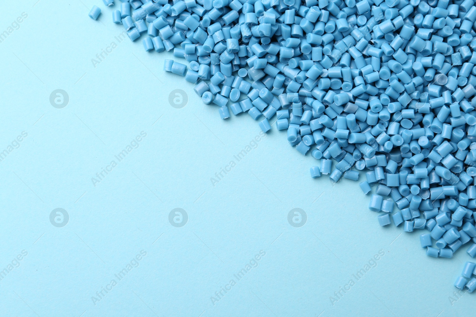 Photo of Pile of plastic granules on light blue background, top view. Space for text