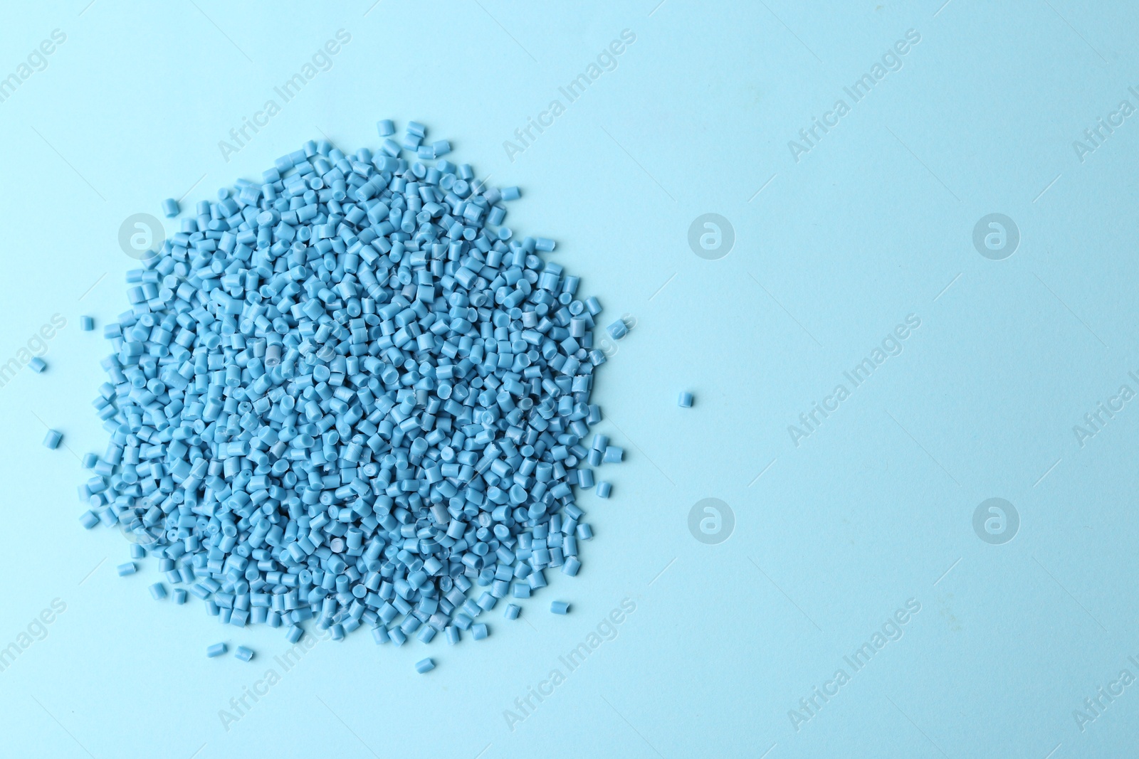 Photo of Pile of plastic granules on light blue background, top view. Space for text