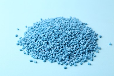 Pile of plastic granules on light blue background, closeup