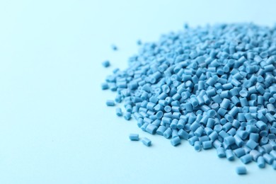 Pile of plastic granules on light blue background, closeup. Space for text