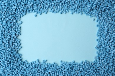 Frame of plastic granules on light blue background, top view. Space for text