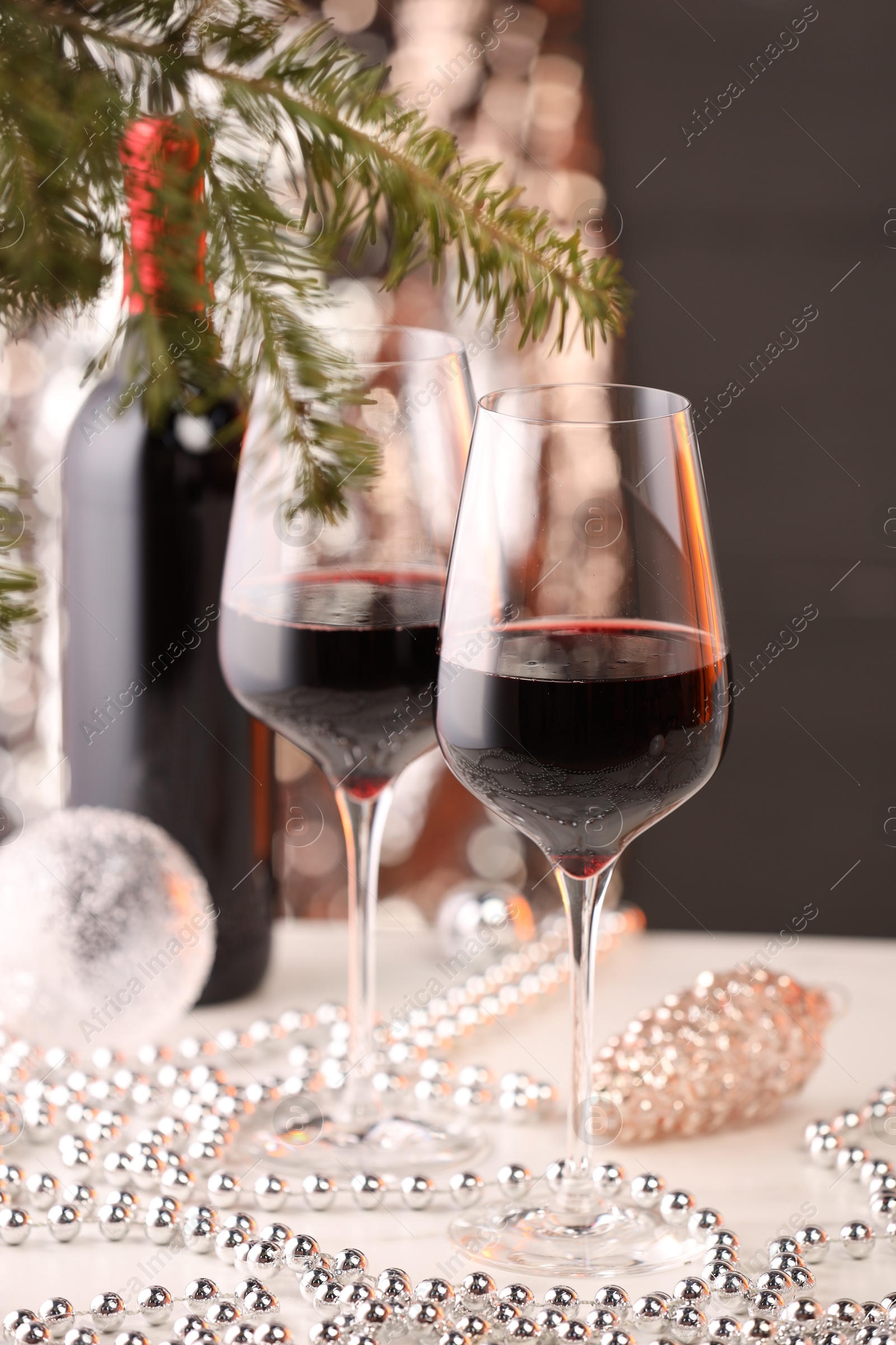 Photo of Red wine and beautiful Christmas decor on white table, closeup