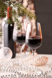 Photo of Red wine and beautiful Christmas decor on white table, closeup