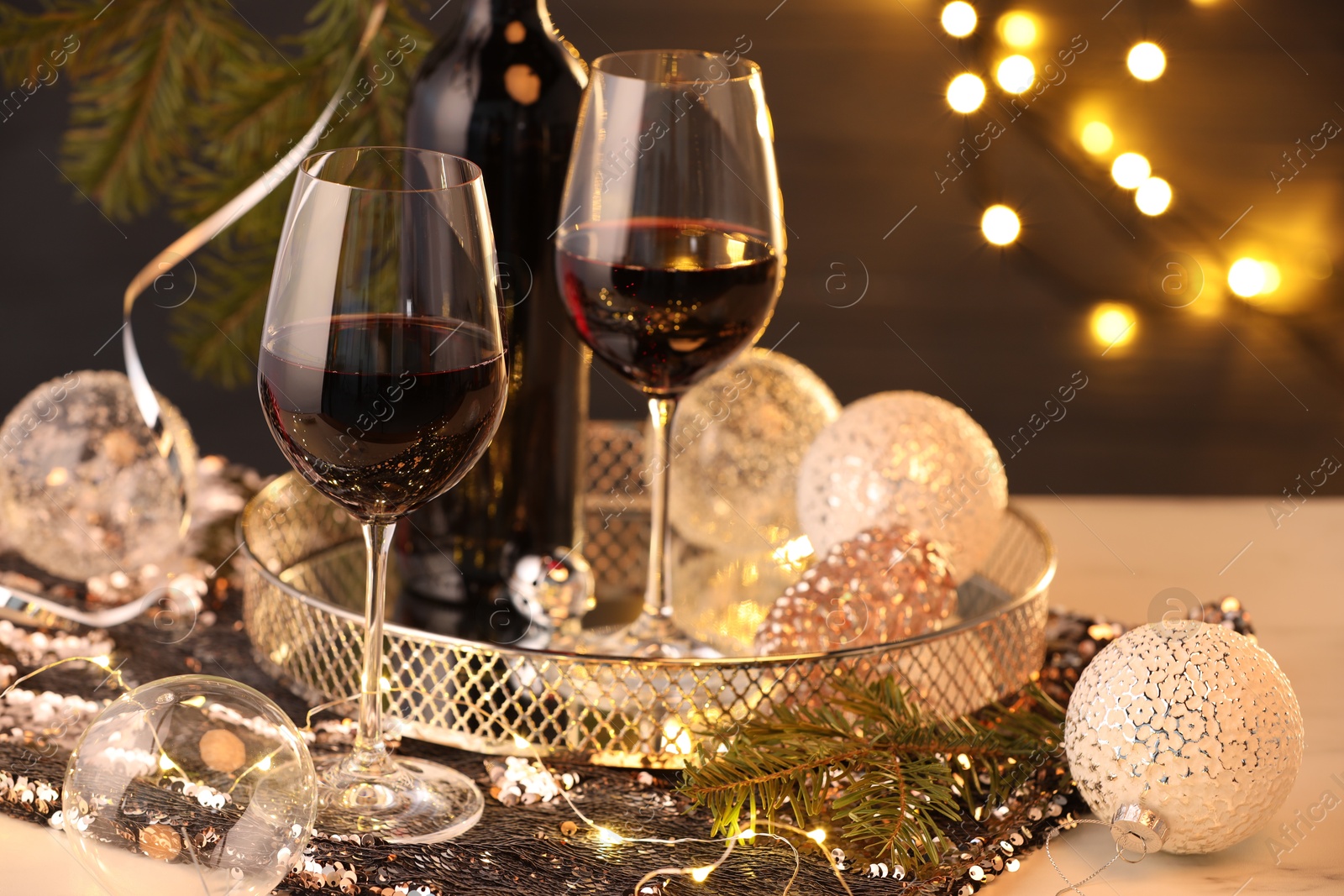 Photo of Red wine and beautiful Christmas decor on white table, closeup