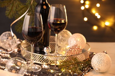 Photo of Red wine and beautiful Christmas decor on white table, closeup