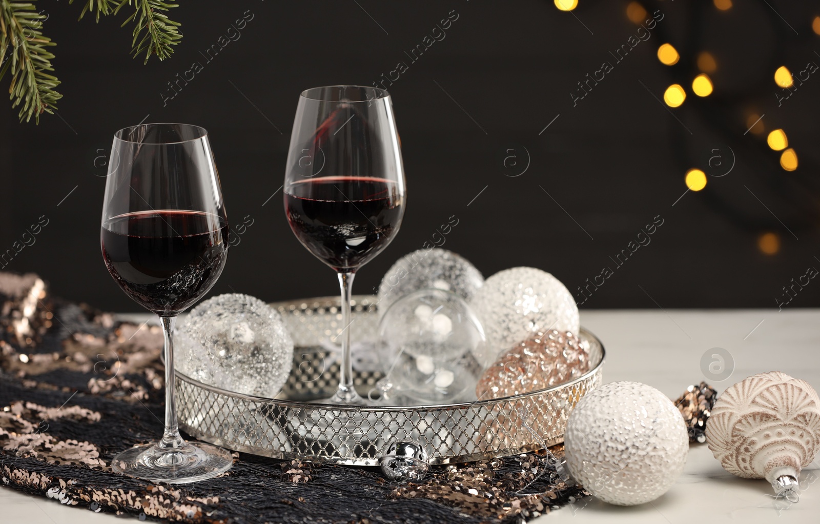 Photo of Glasses with red wine and beautiful Christmas decor on white table