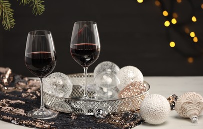 Photo of Glasses with red wine and beautiful Christmas decor on white table