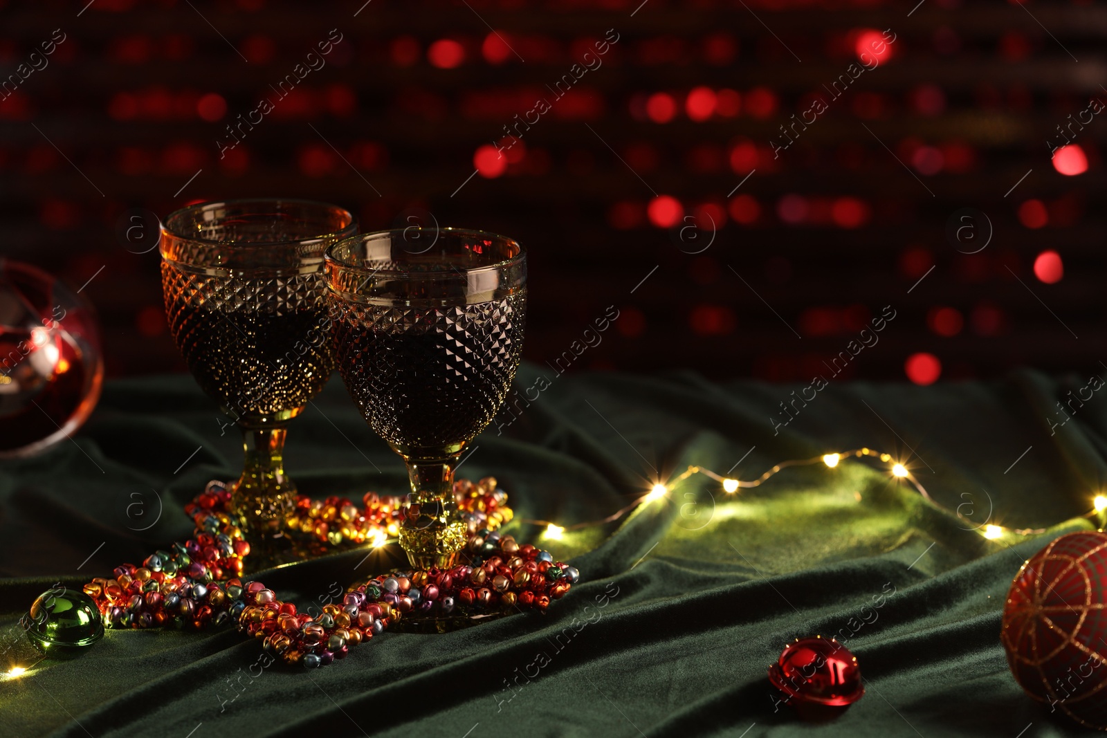 Photo of Glasses with red wine and beautiful Christmas decor on table. Space for text