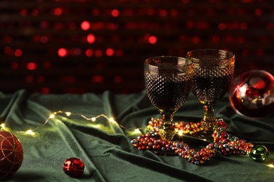 Photo of Glasses with red wine and beautiful Christmas decor on table. Space for text