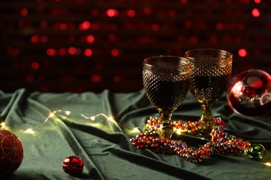 Photo of Glasses with red wine and beautiful Christmas decor on table. Space for text