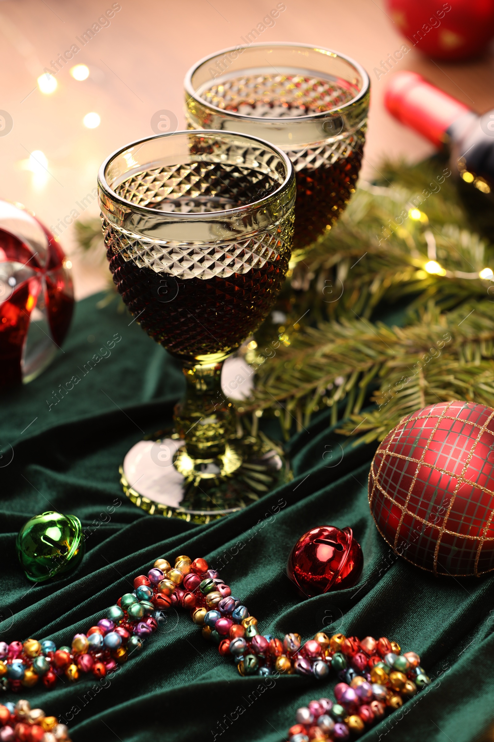 Photo of Glasses with red wine and beautiful Christmas decor on table, closeup