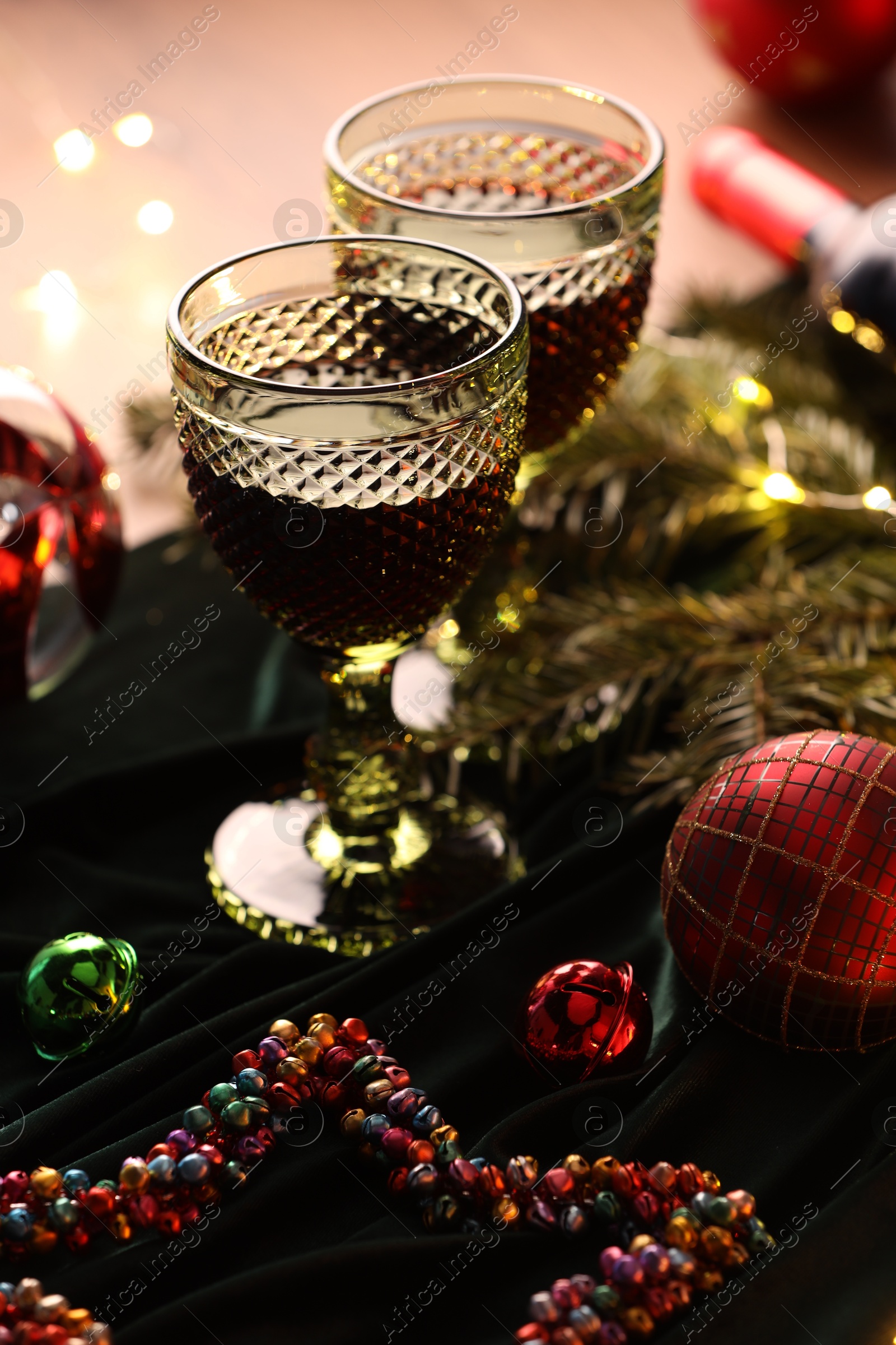 Photo of Glasses with red wine and beautiful Christmas decor on table, closeup