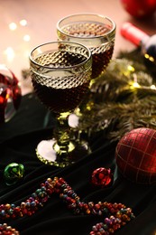 Photo of Glasses with red wine and beautiful Christmas decor on table, closeup