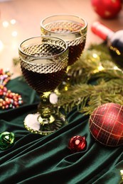 Photo of Glasses with red wine and beautiful Christmas decor on table, closeup