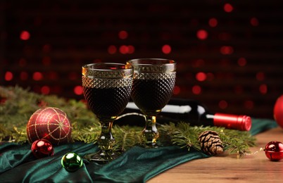 Photo of Glasses with red wine and beautiful Christmas decor on wooden table