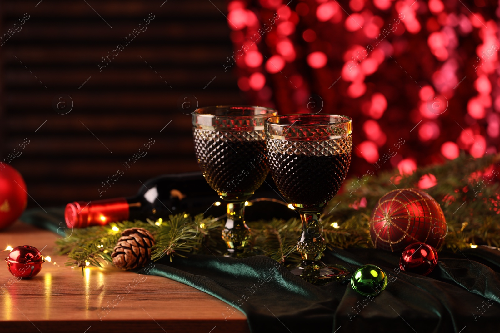 Photo of Glasses with red wine and beautiful Christmas decor on wooden table