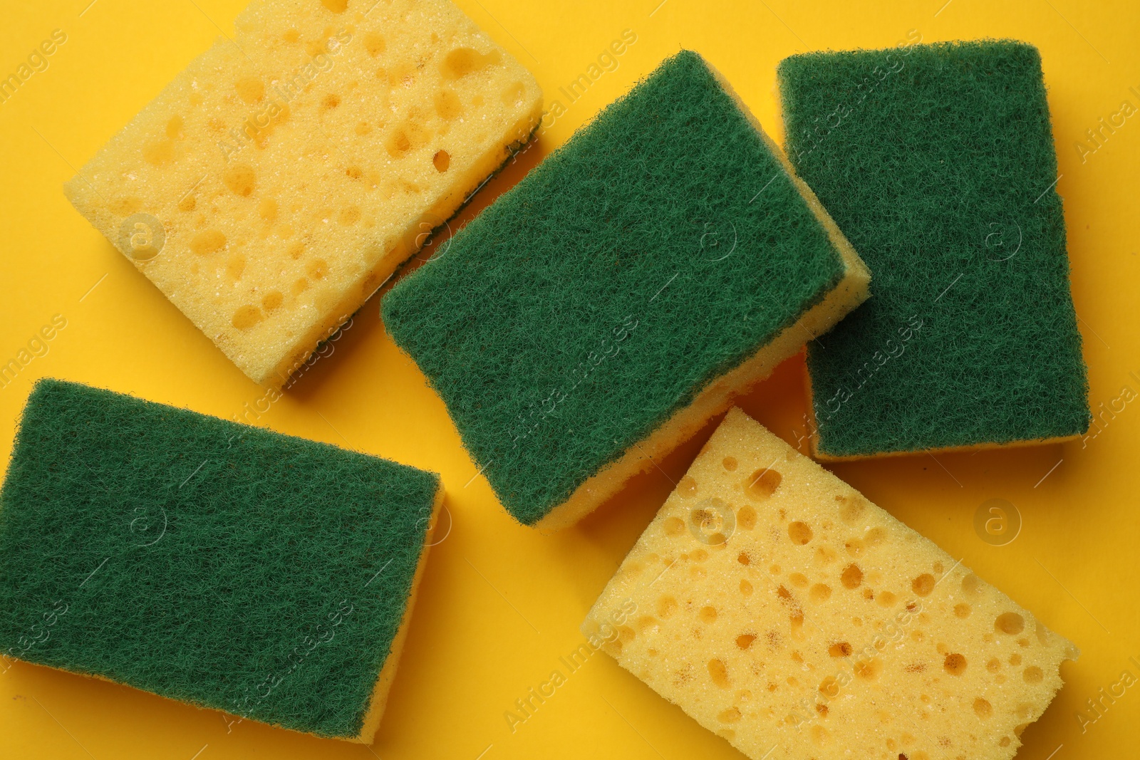 Photo of Soft sponges on yellow background, flat lay. Cleaning tool