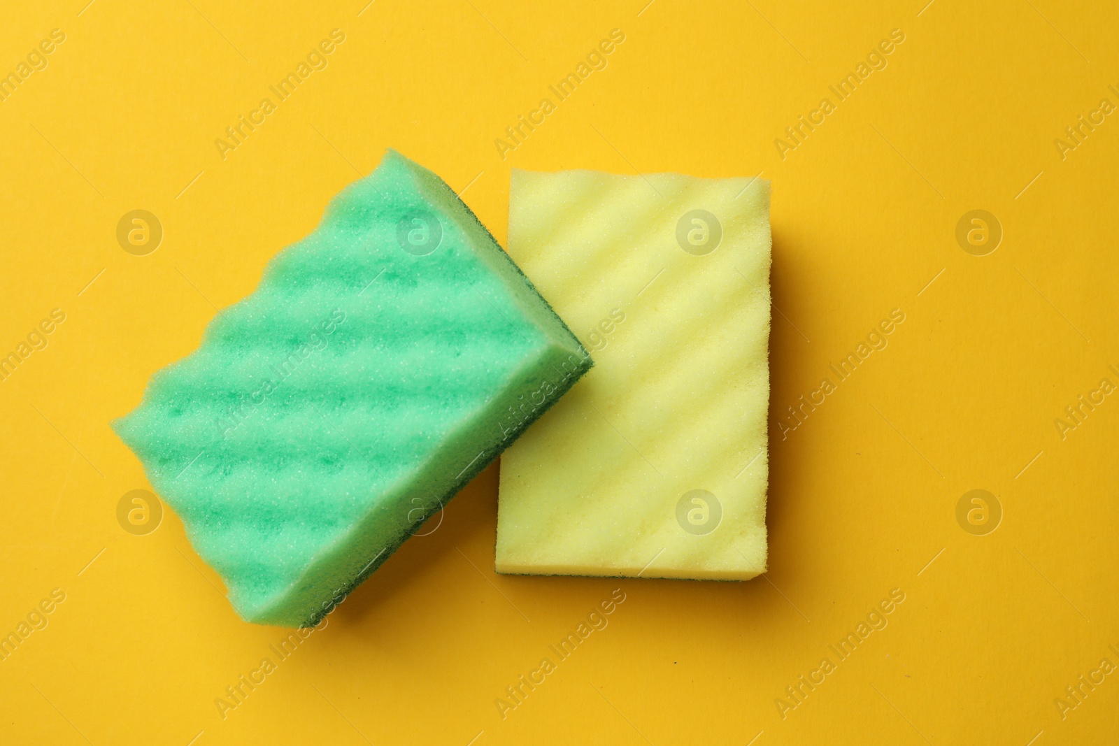 Photo of Soft sponges on yellow background, top view. Cleaning tool