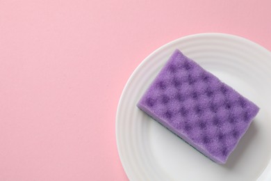 Photo of Plate with sponge on pink background, top view. Space for text