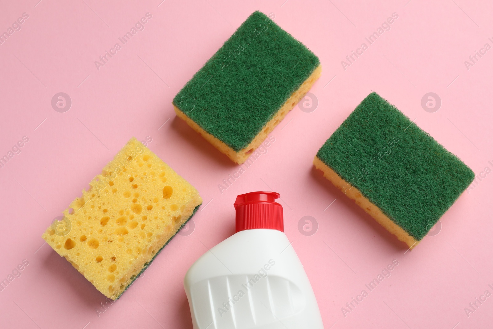 Photo of Sponges and dish soap on pink background, flat lay