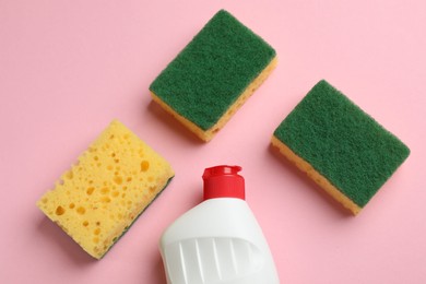 Photo of Sponges and dish soap on pink background, flat lay