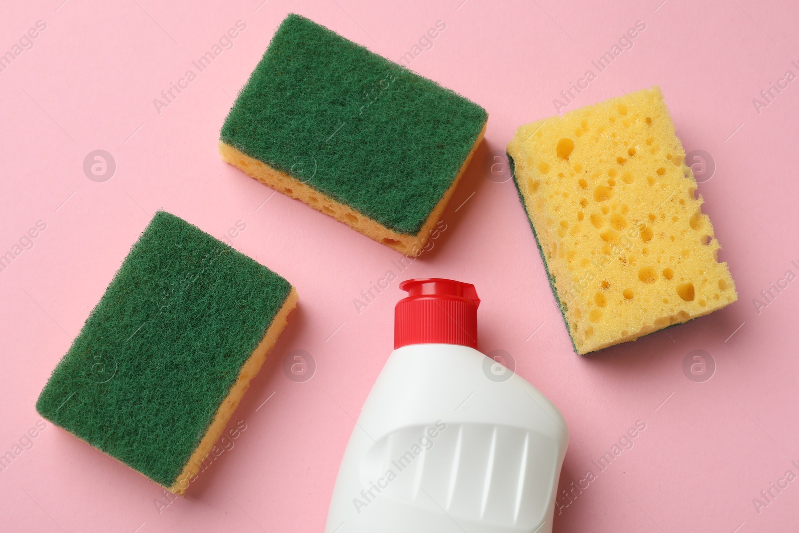 Photo of Sponges and dish soap on pink background, flat lay