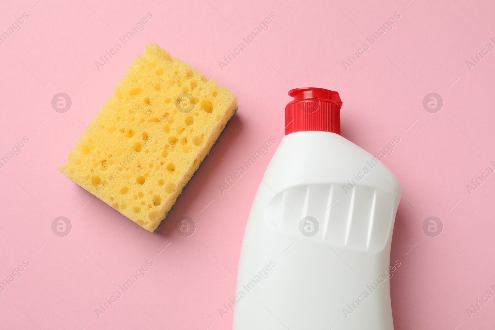 Photo of Sponge and dish soap on pink background, top view