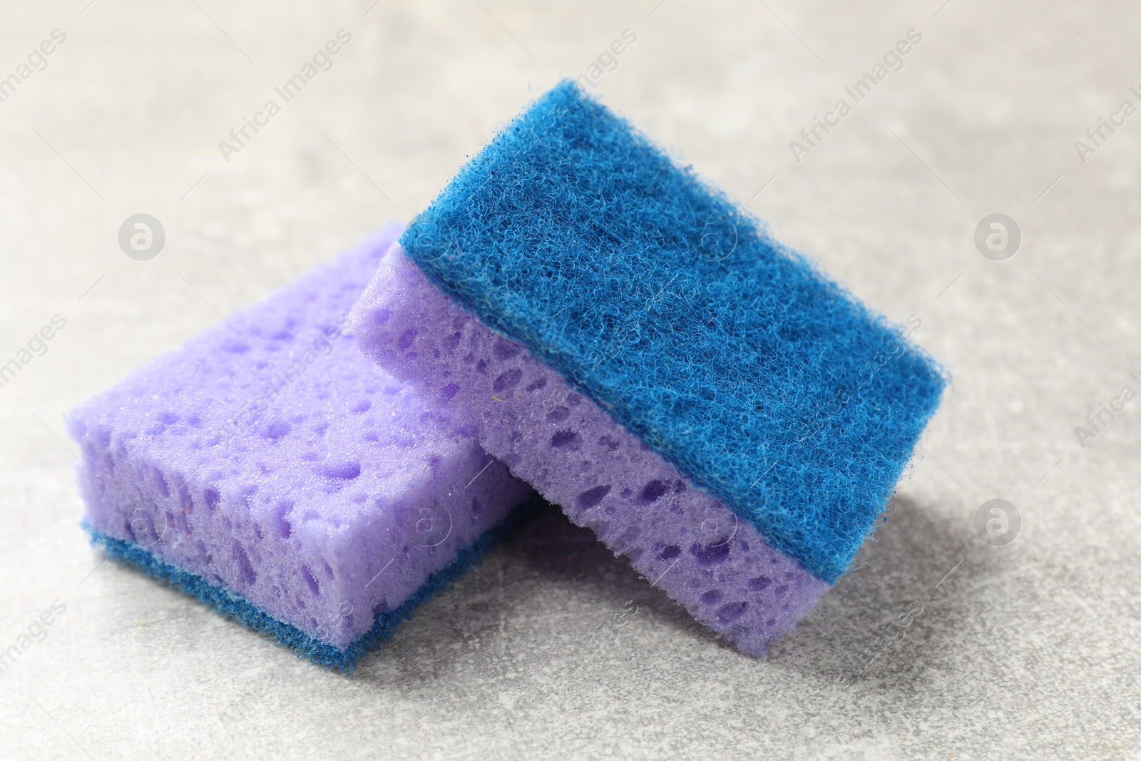 Photo of Soft sponges with foam on gray textured table, closeup