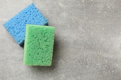 Photo of Soft sponges with foam on gray textured table, top view. Space for text