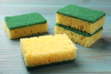 Photo of Soft sponges on light blue wooden table, closeup