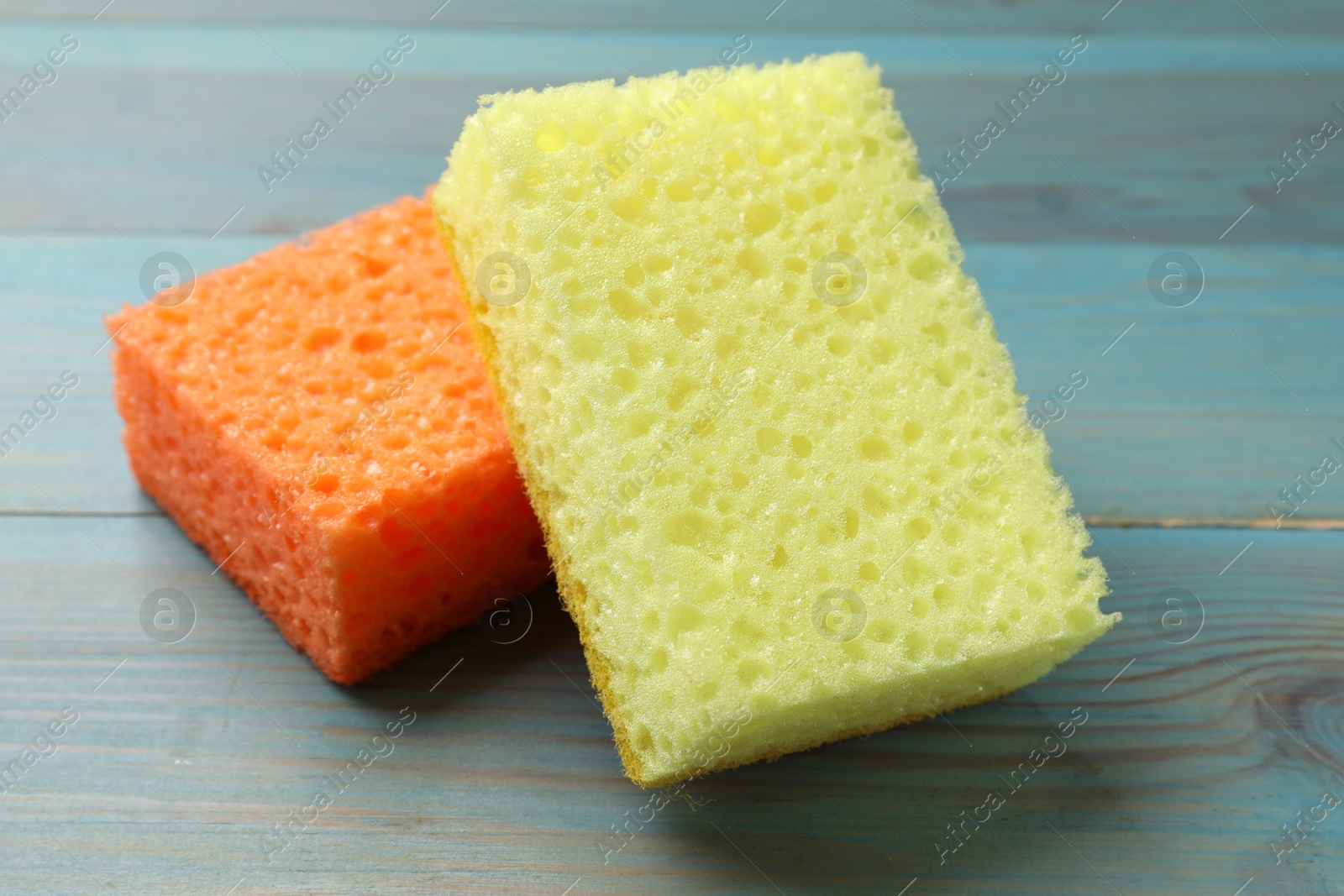 Photo of Soft sponges on light blue wooden table, closeup