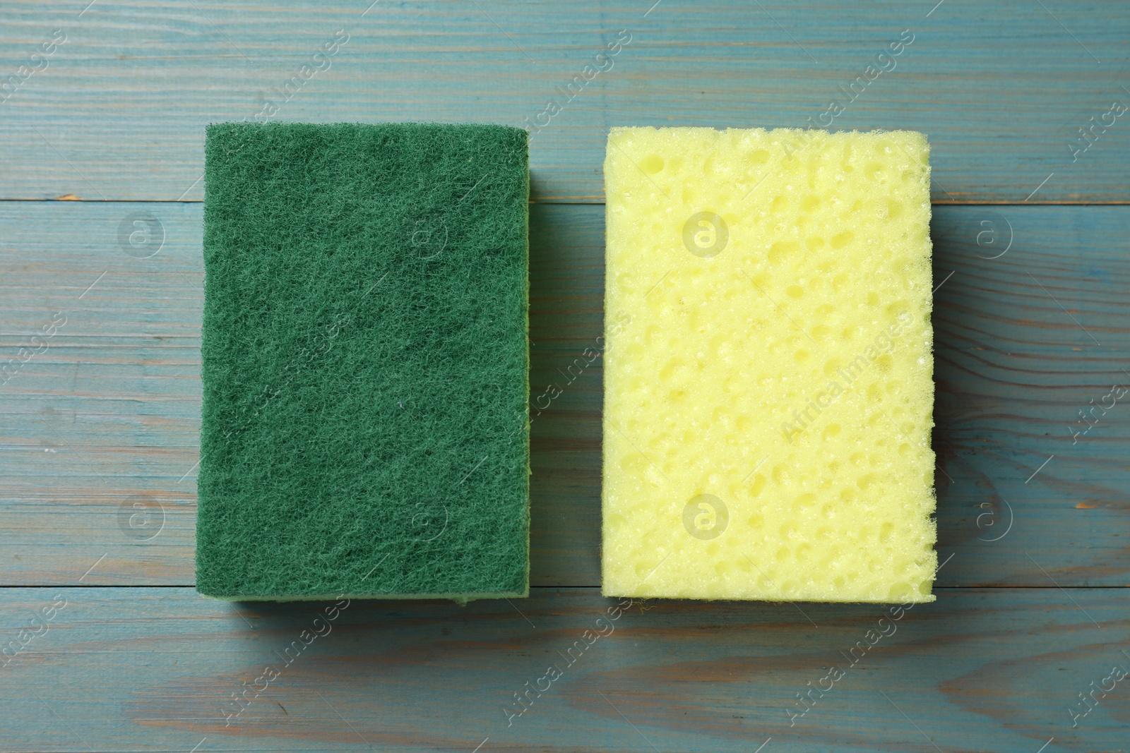 Photo of Soft sponges on light blue wooden table, top view