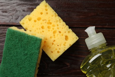 Photo of Soft sponges and dish soap on wooden table, flat lay