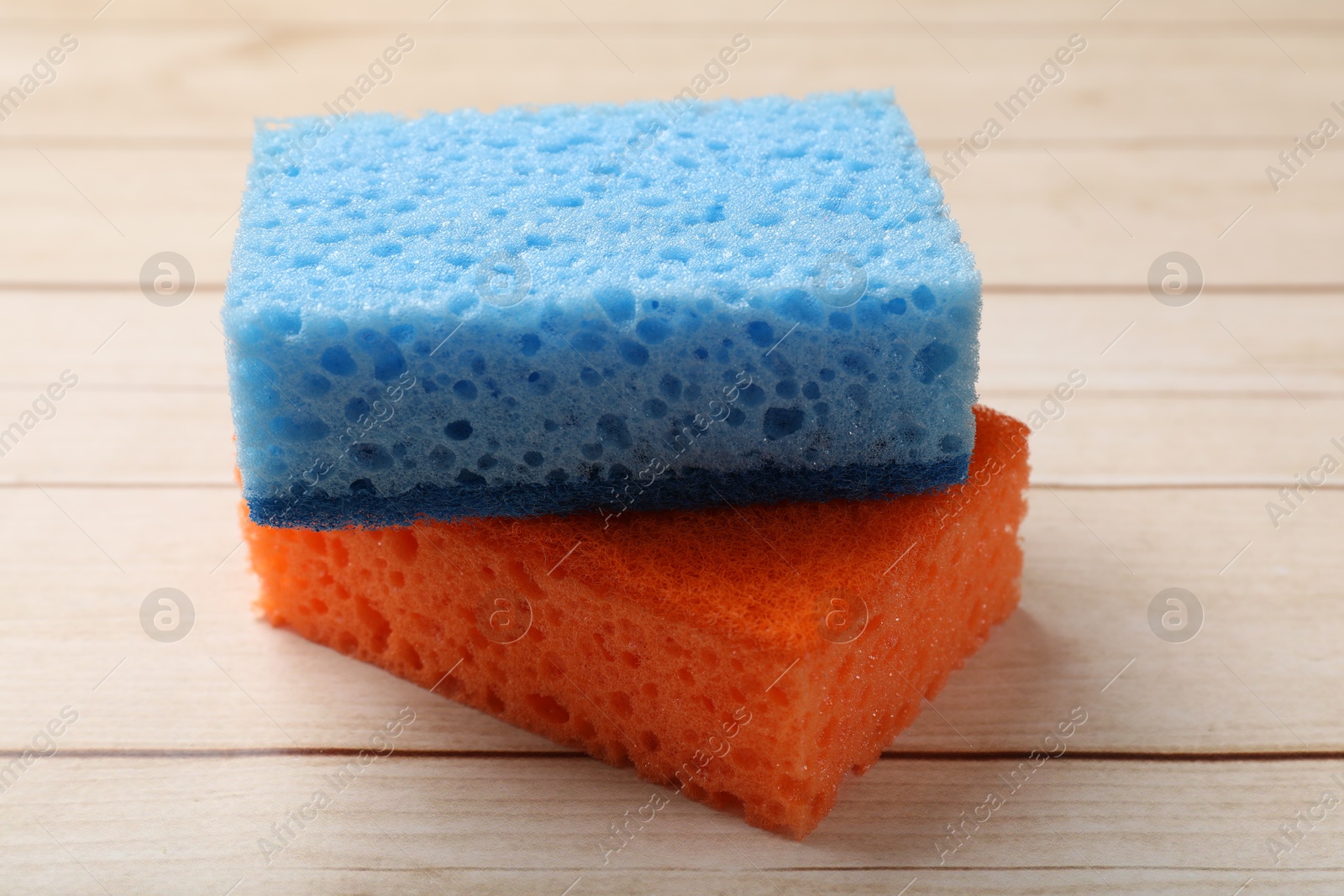 Photo of Two soft sponges on wooden table, closeup