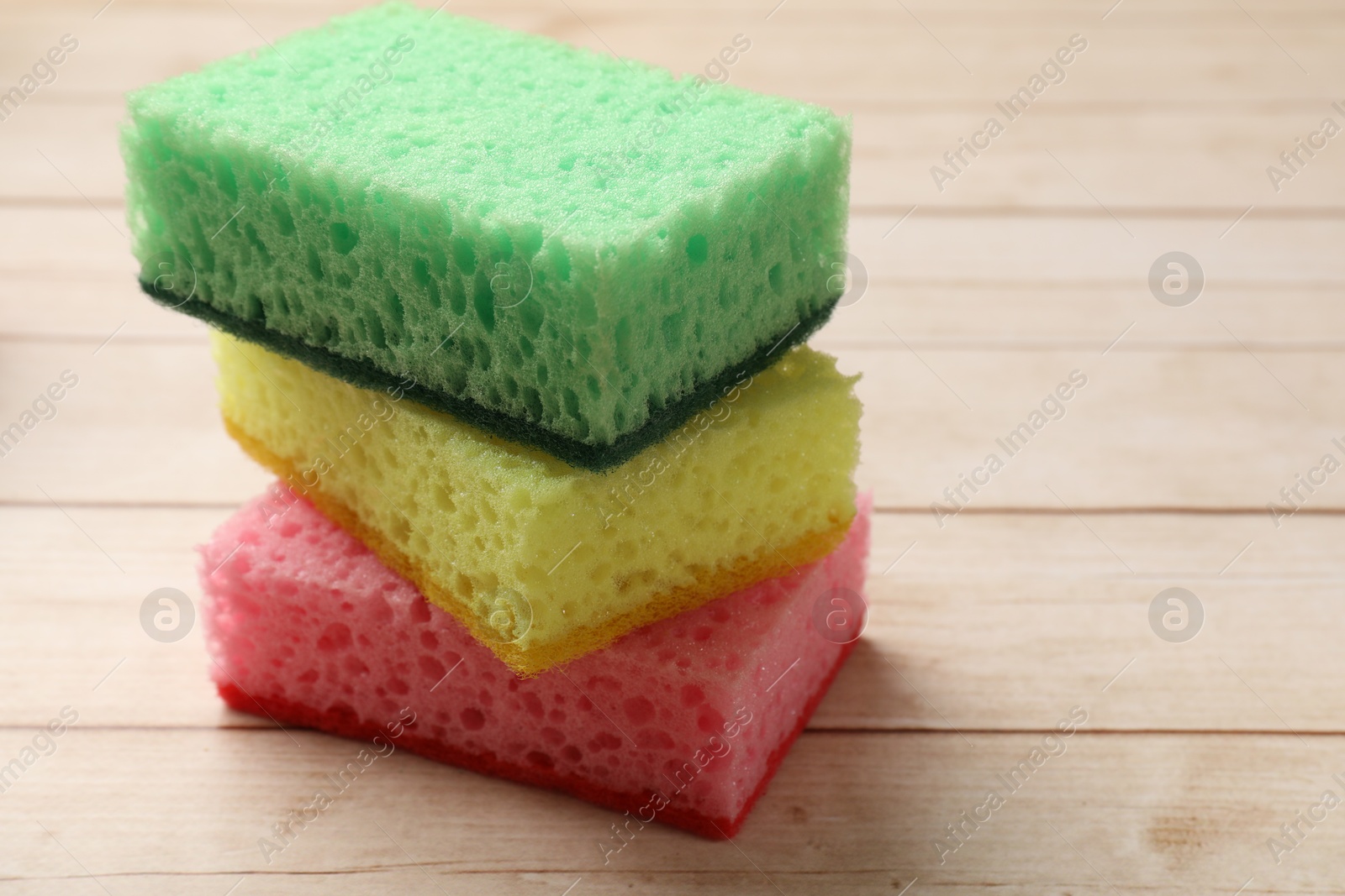 Photo of Soft sponges on wooden table, closeup. Space for text