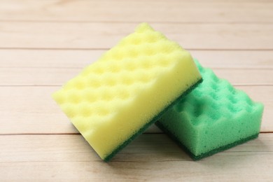 Photo of Two soft sponges on wooden table, closeup