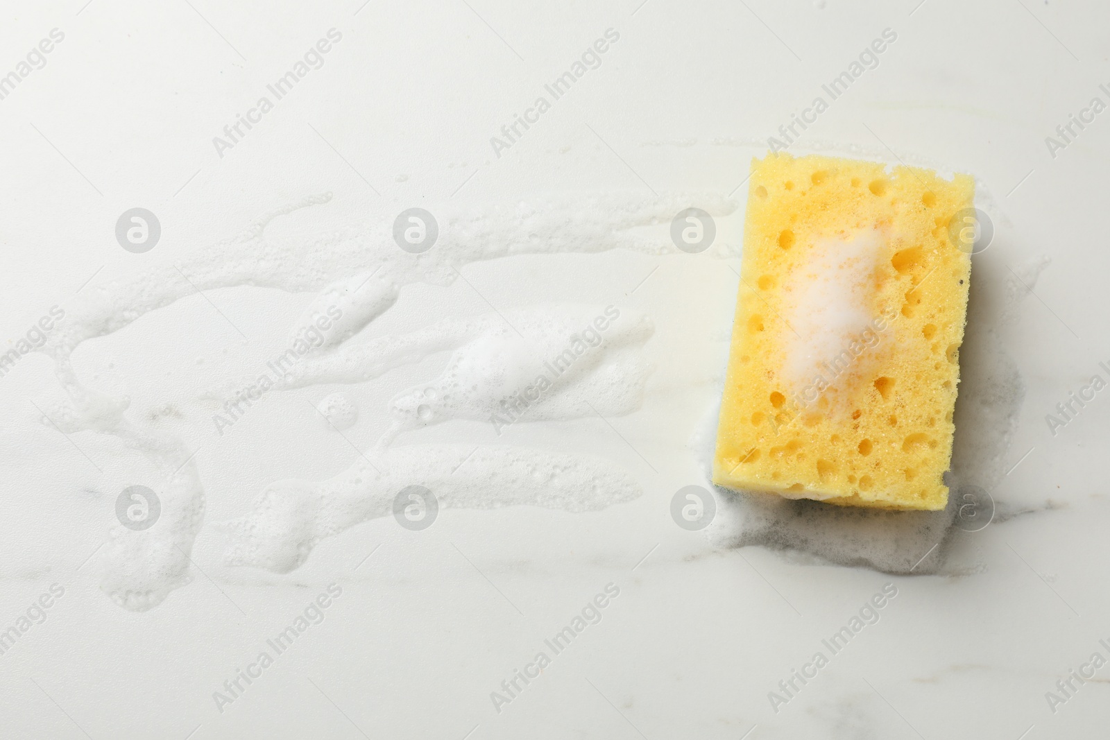 Photo of Yellow sponge with foam on white background, top view. Space for text