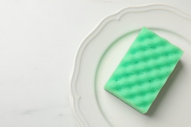 Photo of Green sponge, and plate on white table, top view. Space for text