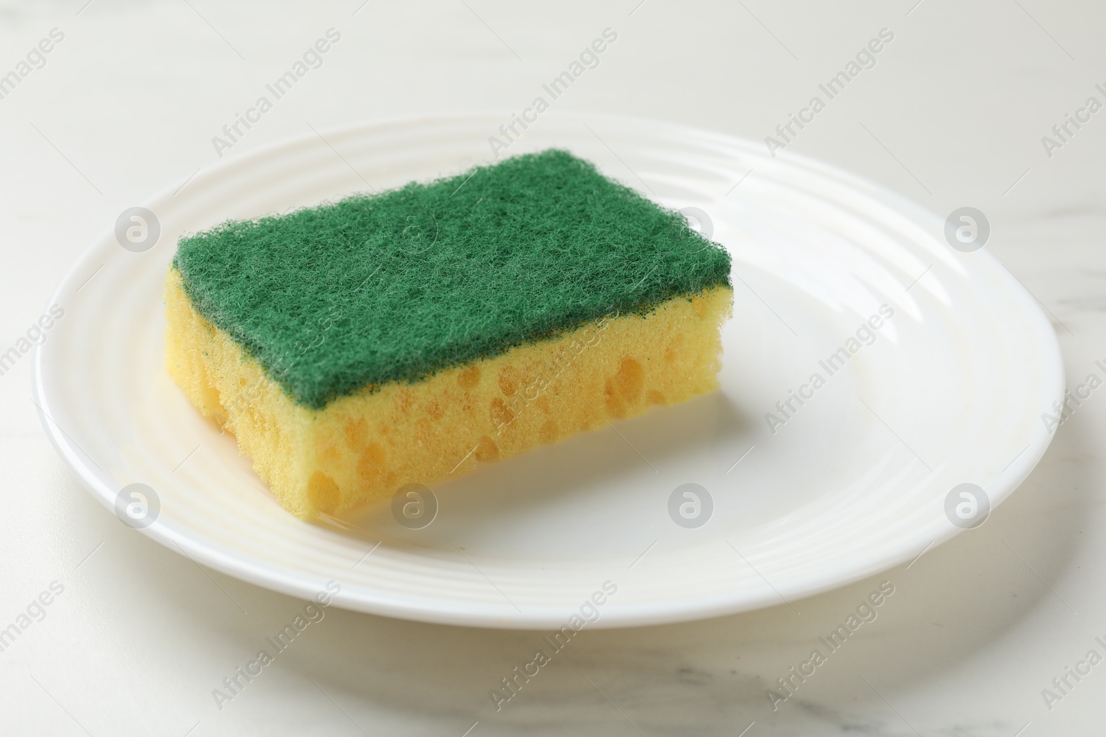 Photo of Soft sponge and plate on white table, closeup