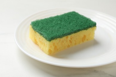 Photo of Soft sponge and plate on white table, closeup