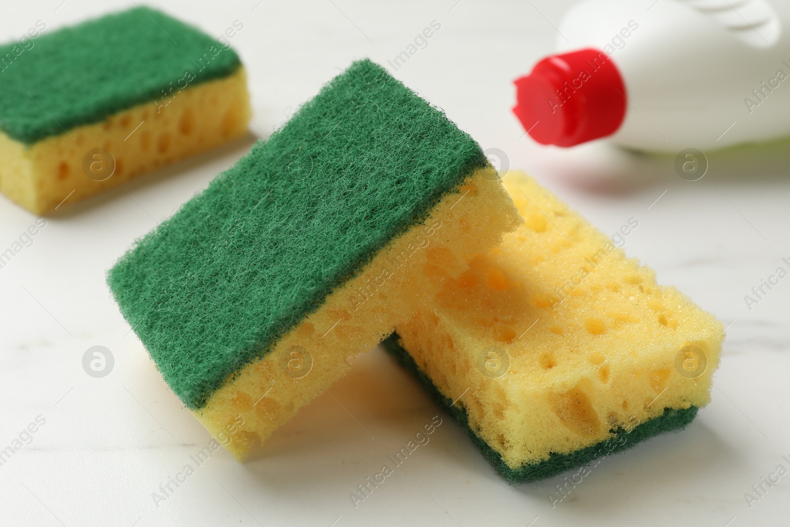 Photo of Soft sponges and dish soap on white table, closeup