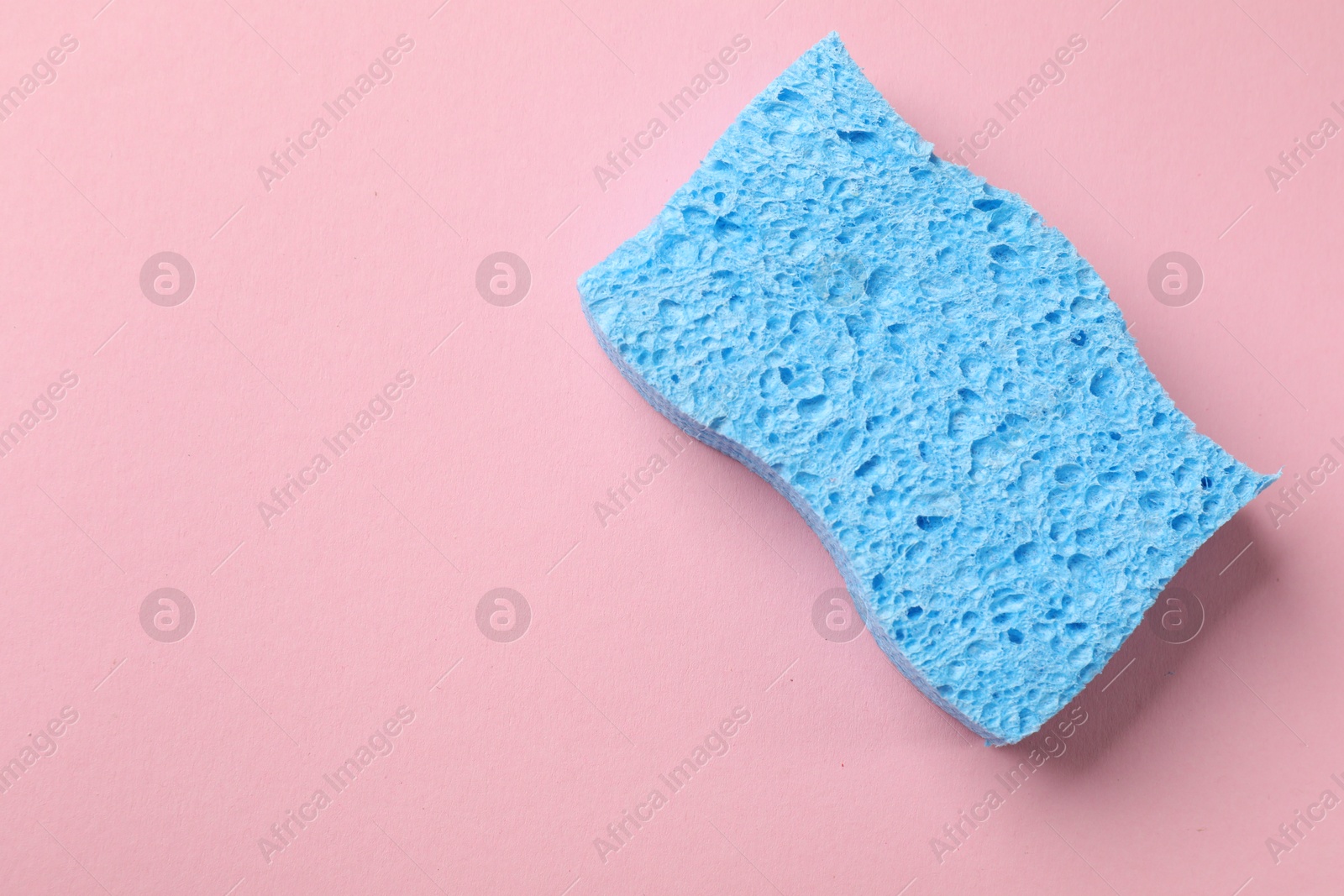 Photo of Light blue sponge on pink background, top view. Space for text