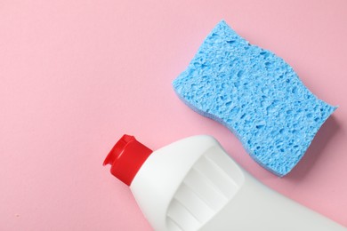 Photo of Light blue sponge and dish soap on pink background, flat lay. Space for text