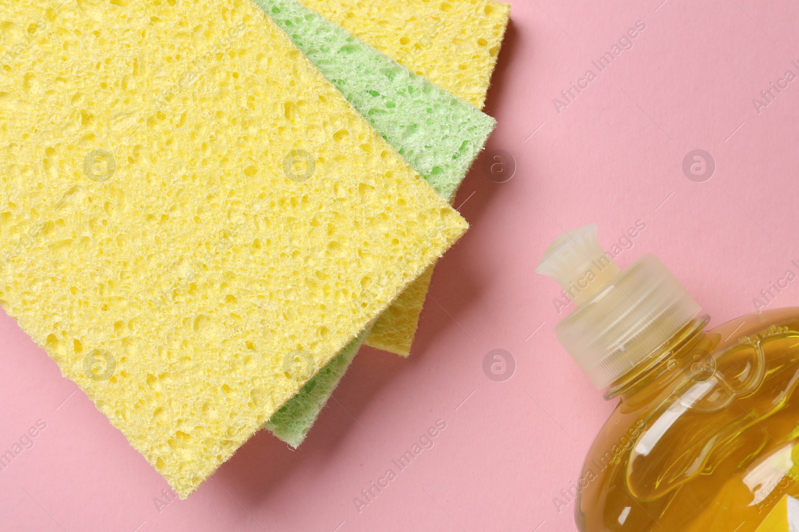 Photo of Soft sponges and dish soap on pink background, flat lay